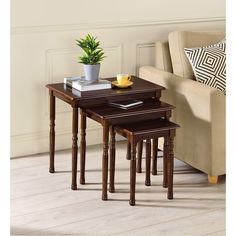 three nesting tables with plant and books on them in front of a couch or chair