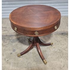 a round wooden table sitting on top of a cement floor next to a garage door