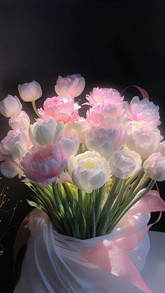 a bouquet of pink and white flowers in a vase on a black background with a pink ribbon