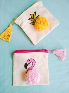 two small pouches with pom poms on them, one pink and one yellow