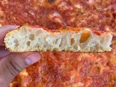 a piece of bread with olives on it being held by someone's hand