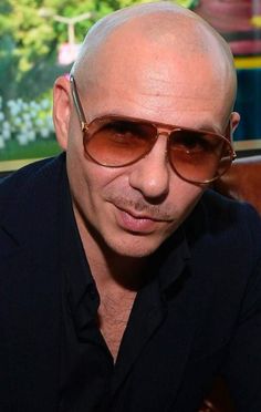 a bald man wearing sunglasses sitting in front of a window