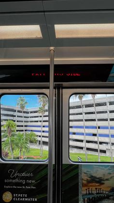 the inside of a subway car with palm trees and buildings in the backround