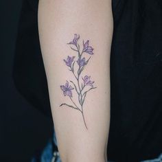 a woman's arm with purple flowers tattooed on the left side of her arm