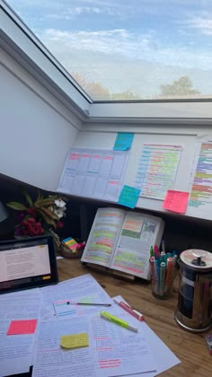 an open book sitting on top of a wooden desk next to a cup filled with pens and paper