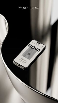 a cell phone sitting on top of a glass table next to a silver vase with the words moyo studio written on it