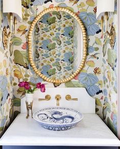 a bathroom sink sitting under a mirror next to a wall mounted faucet with flowers on it