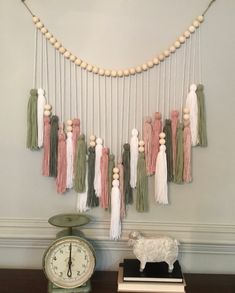 a clock and some tassels hanging on the wall next to a string of beads