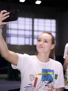 a woman taking a selfie with her cell phone while standing next to another person