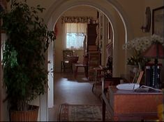 an archway leading to a living room and dining room area with chairs, table, bookshelf and potted plant