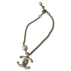 Bracelet signed Chanel, made of gold metal. Equipped with a hook closure. Fitted with a small two-tone CC logo pendant charm. It seems in perfect conditions. Pearl Logo, Chanel Pearls, Chanel Logo, Jewelry Roll, Small Accessories, Vintage Chanel, Coco Chanel, Fashion Handbags, Purse Wallet