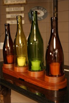 four different colored glass bottles sitting on top of a wooden shelf