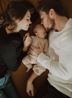 a man and woman are holding a baby in their arms while looking at each other