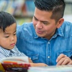 a man reading a book to a young boy