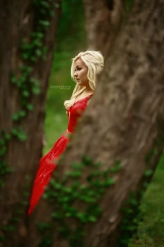 a woman in a red dress standing next to a tree