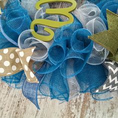 a close up of a wreath on a wooden surface with the letter s and two bows