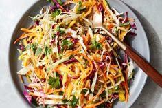 a salad with carrots, lettuce and other vegetables on a gray plate