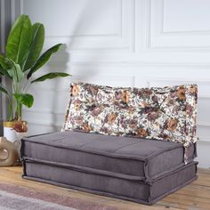 a gray couch sitting on top of a wooden floor next to a potted plant