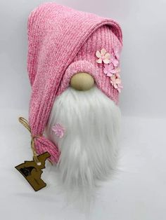 a pink and white gnome hat with flowers on it's head, next to a keychain