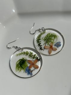 Gorgeous colorful wildflowers  with delicate ferns hand picked, pressed and dried for 2-3 days.   Once dried, I began the process of creating one of kind pieces which are preserved in a high quality non-toxic two part resin.  They are set in an open back hoop bezel, measuring 1-5/8 inch in diameter with silver earring wires. They are lightweight, beautiful and perfect for any occasion. ** Happy to answer any questions you may have, and invite you to share your thoughts on these special botanical earrings OR if you're interested in a custom or personalized version! Send me a message - I love connecting with customers! ** As in nature, there may be differences in shape, color or foraged elements.  Each item is unique therefore the piece you receive might not be exactly as shown in photos.  T Bohemian Dangle Earrings With Pressed Flowers, Nature-inspired Flower Earrings, Nature-inspired Round Pressed Flowers Earrings, Botanical Flower Earrings With Flower Charm, Bohemian Pressed Flower Earrings, Delicate Pressed Flower Earrings, Nature-inspired Dangle Earrings With Pressed Flowers, Botanical Flower Earrings With Birth Flower, Bohemian Flower Earrings With Pressed Flowers