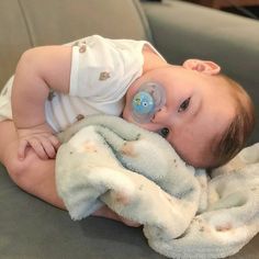 a baby laying on top of a couch with a pacifier in it's mouth