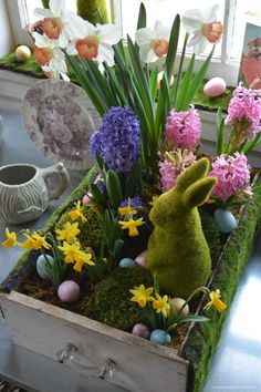 a wooden box filled with fake flowers and an easter bunny figurine sitting on top of it