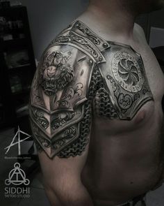 a man's chest with an armor and lion tattoo on his left arm, which is