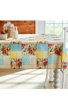 a table with a flowered tablecloth on it and some bowls of cereal in the background