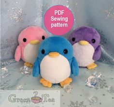 three small stuffed penguins sitting next to each other on a table with snowflakes