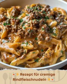 a white bowl filled with pasta covered in ground beef and gravy on top of a wooden table