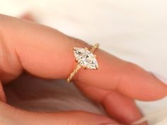 a woman's hand holding a diamond ring