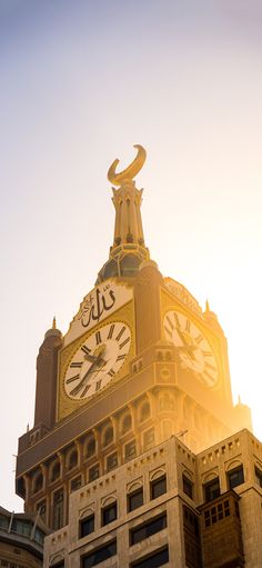 a large clock tower on top of a building with the sun shining in the background