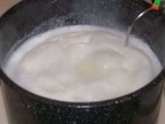 a black bowl filled with white liquid on top of a counter