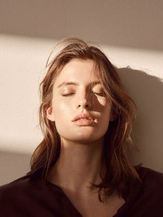 a woman with her eyes closed standing in front of a wall