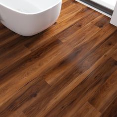 a bathtub sitting on top of a wooden floor next to a window and door