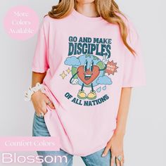 Retro World & Heart Character Bible Verse Christian Unisex Comfort Colors® T-Shirt - Matthew : 28-19 ( With so many color options, if you are struggling to pick one or would like to see one not listed or the design more up-close a color, please reach out and we will check availability or send you some pics. Celebrate the heart and soul of teaching with our beautifully designed Comfort Colors T-Shirt.  Crafted for comfort and style, this tee features a stunning retro world and heart character wit Pink Heart Graphic Short Sleeve T-shirt, Pink Cotton T-shirt With Heart Graphic, Relaxed Fit Crew Neck Shirt With Heart Graphic, Relaxed Fit Short Sleeve Top With Heart Graphic, Pink Relaxed Fit T-shirt With Slogan, Pink Short Sleeve Top With Heart Graphic, Pink Short Sleeve T-shirt With Heart Graphic, Pink Short Sleeve Shirt With Heart Graphic, Relaxed Fit Short Sleeve Shirt With Heart Graphic