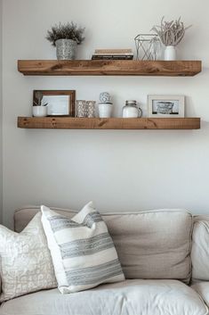 two wooden shelves on the wall above a white couch with pillows and throw pillows in front of it