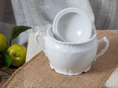 three white bowls are stacked on top of each other in front of some green apples