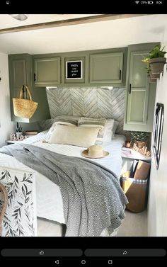 a bed sitting in the middle of a bedroom next to green cupboards and drawers