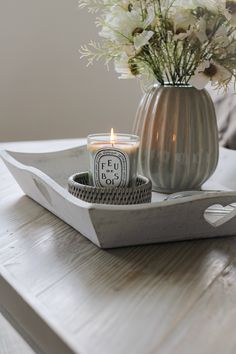 a candle is sitting on a tray with flowers