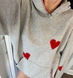 a woman wearing a gray hoodie with red hearts on it