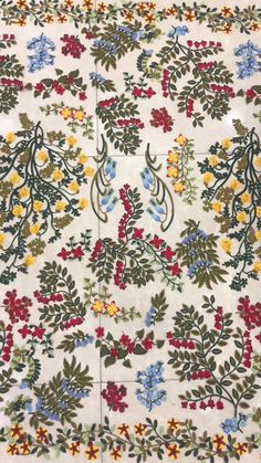 an embroidered tablecloth with flowers and leaves on white fabric, showing the design in different colors