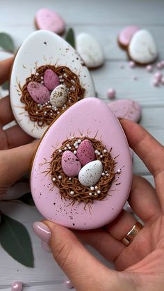 two decorated eggs in the shape of birds'nests with pink and white speckles