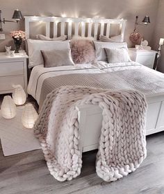 a white bed topped with lots of pillows and blankets on top of it's headboard