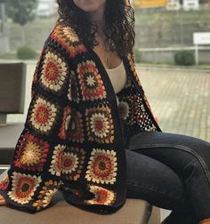 a woman sitting on top of a wooden bench wearing a crocheted granny hat