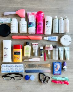 an assortment of personal care items laid out on a wooden table with sunglasses, toothbrushes, and other hygiene products