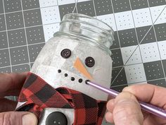 a person is making a snowman out of a mason jar with a purple pencil