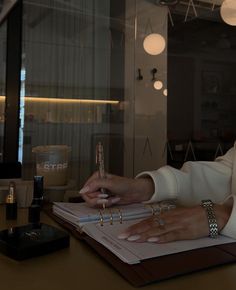 a woman sitting at a desk writing on a notebook