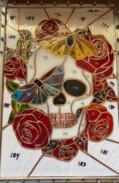 a stained glass mosaic with a skull and roses on it's side, in the shape of a human head