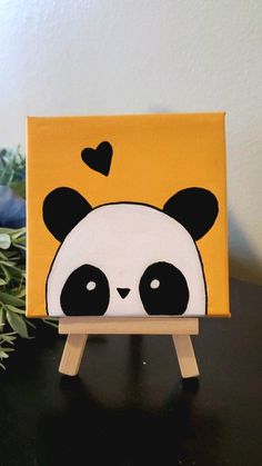 a painting of a panda bear with hearts on it's head sitting on a wooden easel